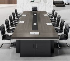 an empty conference table with black chairs and a white marble wall behind it in the middle of a large room