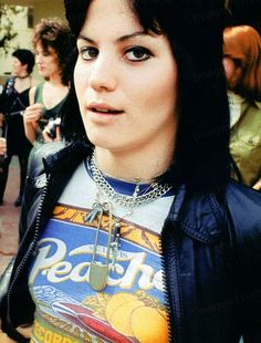 a woman with black hair wearing a pepsi t - shirt and some people in the background