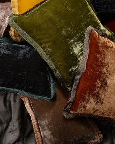 four different colored velvet pillows stacked on top of each other