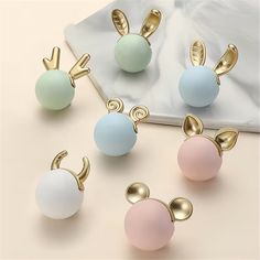 four pairs of bunny ears with pastel blue, pink and white balls on them