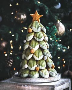 a christmas tree made out of cookies sitting on top of a wooden table next to a christmas tree