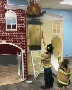 two children playing in a play house with fireman and ladders on the roof