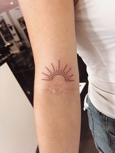 a woman's arm with a small sun tattoo on the left side of her arm