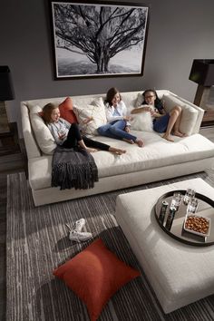 three women sitting on a white couch in a living room next to a coffee table