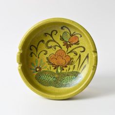 a small yellow bowl with flowers painted on the side and green grass in the middle