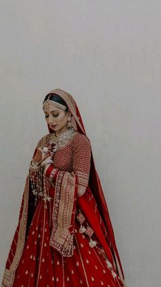 a woman in a red and gold bridal gown is standing with her hands on her hips