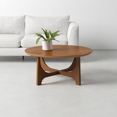 a white couch sitting next to a wooden table with a potted plant on it