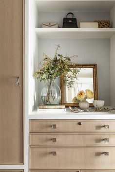 a vase filled with flowers sitting on top of a wooden dresser next to a mirror