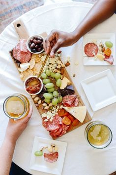 people are eating and drinking wine at a table with food on the plates, including grapes