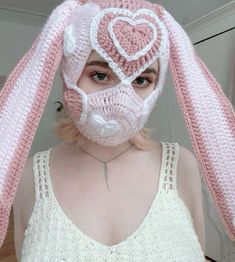 a woman wearing a pink bunny mask with white hearts on it's face and ears