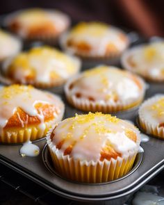 cupcakes with icing and lemon drizzled on them in a muffin tin