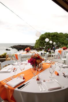 an outdoor dining area with tables and chairs set up for formal function overlooking the ocean