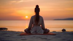 a woman is sitting in the middle of a yoga pose on the beach at sunset