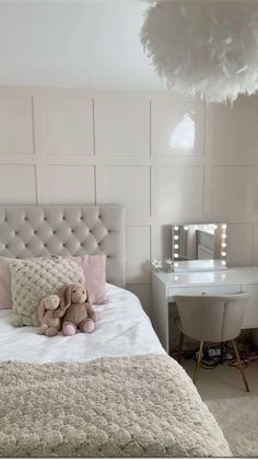 a teddy bear sitting on top of a bed next to a white desk and chair