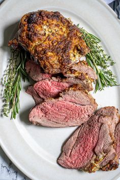 some meat is on a white plate and garnished with herbs