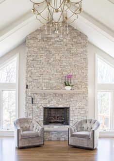 a living room with two chairs and a chandelier in it's center