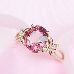 a pink diamond ring sitting on top of a pink flowered surface with diamonds around it