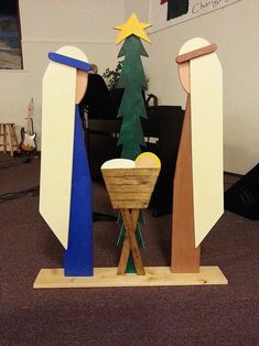 a wooden nativity scene in an office cubicle with a christmas tree and star on top