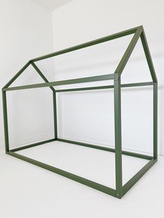 a green glass house sitting on top of a white floor in front of a wall