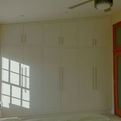 a bedroom with white cupboards and a ceiling fan