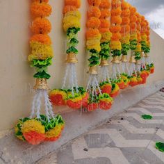 colorful garlands hanging on the side of a wall with bells and flowers attached to them