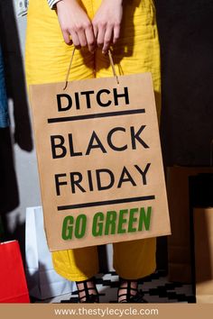 a person in yellow pants holding a sign that says ditch black friday go green on it