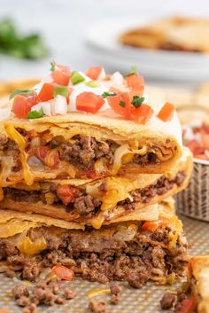 three taco bellitos stacked on top of each other with cheese and toppings