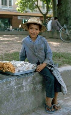 a boy sitting on a ledge with food in front of him and smiling at the camera