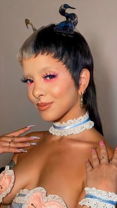 a woman with pink makeup and piercings on her chest posing for the camera while wearing an elaborate outfit