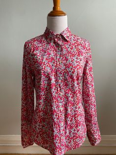 Discover the beauty of "Liberty of London" fabric in this classic J. Crew shirt. The pattern is "Wiltshire", a popular style that has been recolored many times by Liberty. On a pure white ground are images of berries and foliage in madder red, pink, red violet and navy. The shirt is fitted by darts at bust in front, long darts in back and slightly shaped side seams. The collar is short, straight and pointed. Sleeves are long with two button cuffs. Closure is in front via eight buttons. Lower edge is finished in a shirttail hem. Size on label is a 6 and that seems correct. Condition is pristine; no issues whatsoever. Should to Shoulder: 14" Armhole to Armhole: 19" Length: 26" Sleeve Seam: 18.5" Liberty Of London Fabric, Liberty Of London, Crew Shirt, Popular Style, J Crew, Womens Clothing Tops, Blouses For Women, London, Tops & Tees