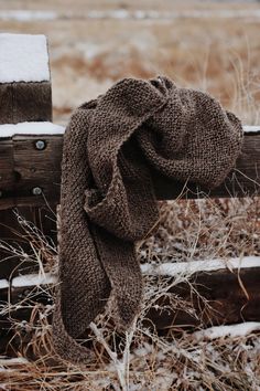 a scarf hanging on a wooden fence in the snow