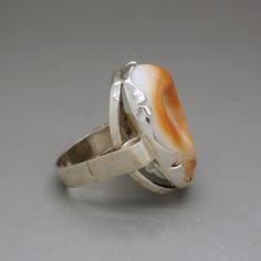 A lovely hallmarked silver ring with a polished curvy sea shell of vivid orange color. An unusual artisan handcrafted statement jewelry item from circa 1970's. The ring will be shipped in a gift box. Ring size: diameter 16.1 mm / US size: 5 1/2 / UK size: L / European - 51 3/4 Ring face measures almost 1 Inch tall (2.4 cm) - it is a true statement ring! Weight: 7.6 grams Hallmarked with a Dutch ZII hallmark for 835 continental silver Excellent vintage condition. The standard shipping for this it Unique Oval Orange Jewelry, Unique Orange Jewelry For Anniversary, Vintage Orange Rings For Collectors, Vintage Orange Ring Jewelry, Unique Orange Ring Jewelry, Orange Vintage Ring Jewelry, Handmade Orange Ring Jewelry, Unique Orange Cabochon Ring, Vintage Handmade Orange Rings