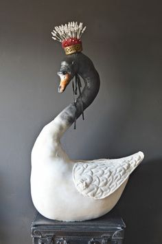 a statue of a swan with a crown on it's head sitting next to a suitcase