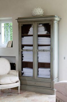 a white chair sitting next to a tall cabinet