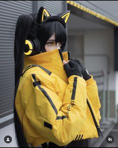 a woman with long black hair wearing a yellow jacket and cat ears on her head