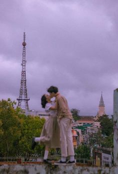 two people are kissing in front of the eiffel tower on a cloudy day