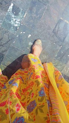 a woman's feet in high heels and a yellow dress with flowers on it