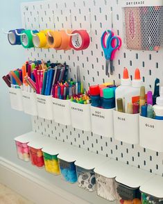 the wall is filled with markers, pens, scissors and other crafting supplies in bins