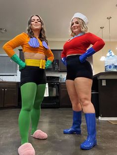 two women dressed in costumes standing next to each other on the floor with their feet up