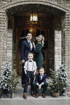 a family posing for a photo in front of a house with christmas decorations on the steps