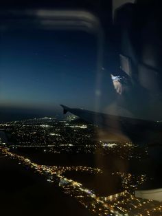 the view from an airplane window at night, looking down on city lights in the distance