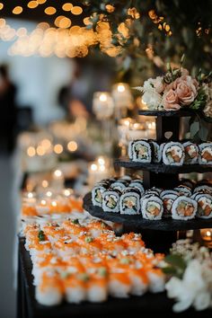 an assortment of sushi is displayed on a table with candles and lights in the background