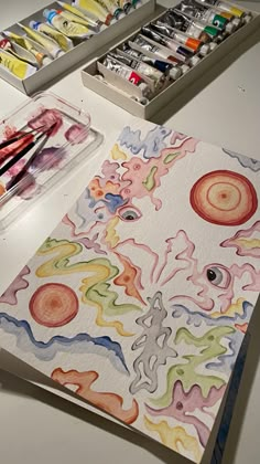 an artist's desk with watercolors and paper