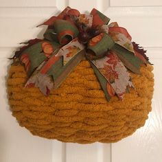 a basket hanging on the front door decorated with fall leaves and ribbons, is ready to be used as a wreath