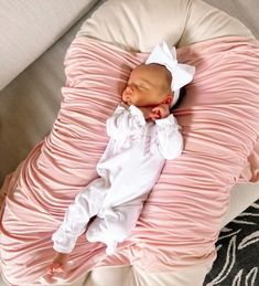 a baby is sleeping on a pillow with pink ruffles and a white headband