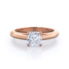 a rose gold engagement ring with a cushion cut diamond in the center, on a white background