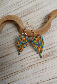 Cheerful ethnic design earrings hand-woven in macramé, combining blue, yellow and brown. They have been made on a gold-coloured metallic base in a hexagonal shape, decorating the fabric with Toho glass seed beads in matte metallic blue. The ear hooks are also gold and boho style. These earrings are ideal for casual, everyday looks. They are also very light. You can see its dimensions in the photographs. Bohemian Yellow Drop Earrings, Yellow Handwoven Drop Earrings, Gold Macrame Earrings For Festival, Gold Woven Dangle Earrings, Handmade Yellow Bohemian Earrings, Adjustable Yellow Macrame Jewelry, Adjustable Yellow Bohemian Earrings, Yellow Handwoven Earrings For Festival, Yellow Handwoven Festival Earrings