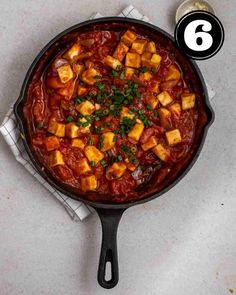 a pan filled with food on top of a white counter next to a spoon and napkin