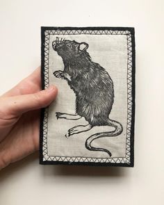 a hand holding up a piece of cloth with a rat on it