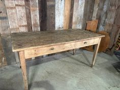 an old wooden table and chair in a room with wood paneling on the walls